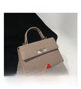 Detail view of khaki stone-textured handbag featuring a gold twist lock and flap closure