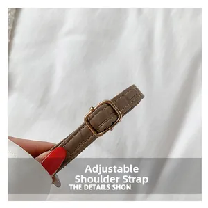Close-up of adjustable brown crocodile texture shoulder strap with gold metal buckle