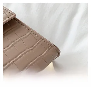 Detail view of taupe crocodile embossed leather texture with gold metal rivets on bag