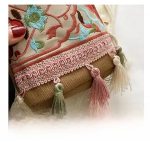 Macro detail of ethnic bucket bag featuring floral embroidery and colorful tassels