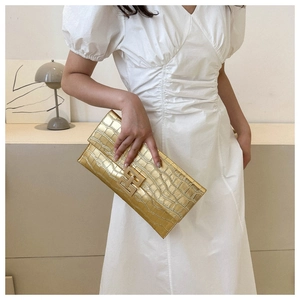 Dettaglio della pochette a busta color oro champagne con motivo a coccodrillo e fibbia