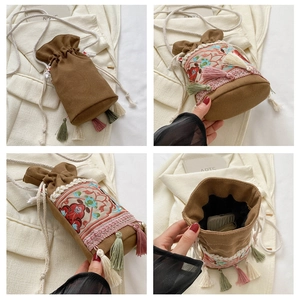 Detailed close-up of bohemian embroidered bucket bag with colorful tassels and floral patterns
