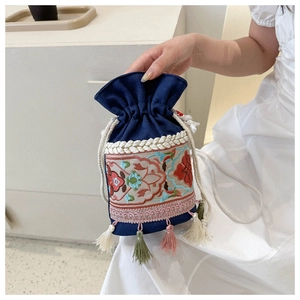 Detail of bohemian floral embroidery and colorful tassels on dark blue bucket bag