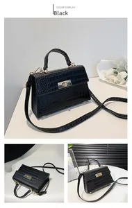 Detail of black crocodile pattern faux leather handbag with golden twist lock closure