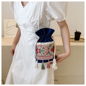 Close-up of ethnic drawstring bucket bag with floral embroidery and colorful tassels