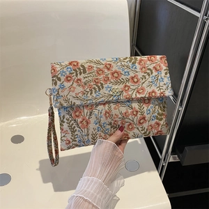 Close-up of vintage floral embroidery fabric and golden flower metal clasp on clutch bag
