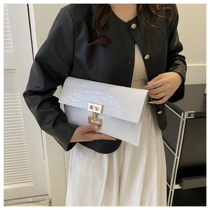 Detail of white crocodile texture envelope clutch bag with elegant golden metal clasp