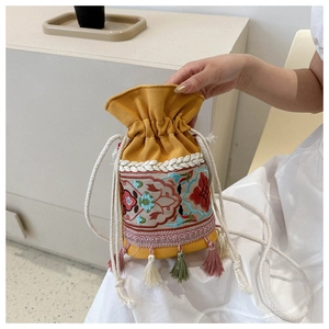 Macro view of ethnic embroidery details and colorful fringe on yellow bucket bag