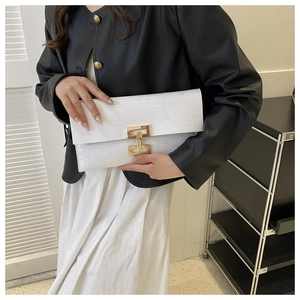 Detail of white envelope clutch with faux crocodile texture and H-shaped gold buckle