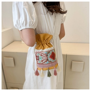 Detail of floral embroidery and colorful tassels on yellow canvas bucket bag