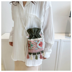 Detail of colorful tassel fringe and floral embroidery on a dark green bucket bag