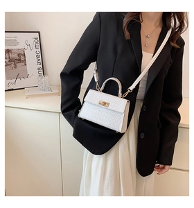 Detail of white crocodile pattern crossbody bag with golden clasp and adjustable strap