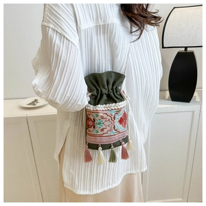 Detail of ethnic embroidered bucket bag with tassels and white cotton rope strap