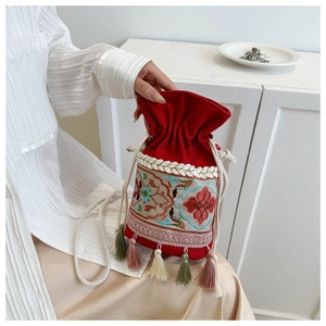 Detailed view of the red bucket bag featuring ethnic embroidery and colorful silk tassels
