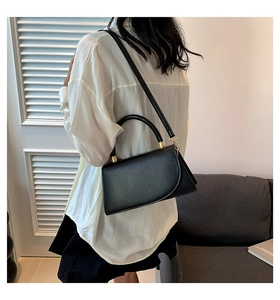 Vista laterale di una borsa in pelle nera opaca con finiture dorate e tracolla regolabile