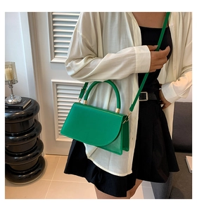 Dettaglio borsa a mano in pelle verde brillante con hardware dorato e patta curva