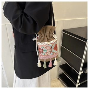 Detail of ethnic embroidery and colorful tassels on a brown canvas bucket bag