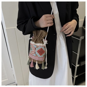 Detail of bohemian bucket bag featuring floral embroidery and colorful tassels