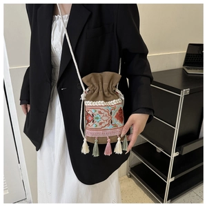Detail of bohemian bucket bag with floral embroidery and colorful hanging tassels