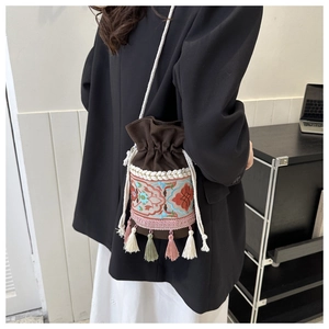 Macro detail of bohemian floral embroidery and colorful tassels on a canvas bucket bag