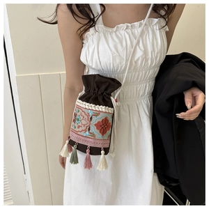 Detail of bohemian bucket bag with floral embroidery and colorful hanging tassels
