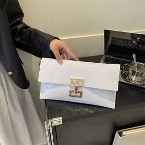 Borsa a busta bianca con trama coccodrillo e fibbia dorata su scrivania da ufficio