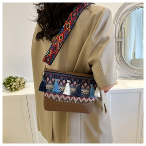 Detail der Bohème-Schultertasche mit gewebtem Riemen und bunten Quastenanhängern am Model
