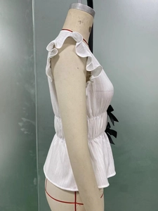 Detail der weißen ärmellosen Bluse mit Rüschenschichten und schwarzen Seifenschleifen