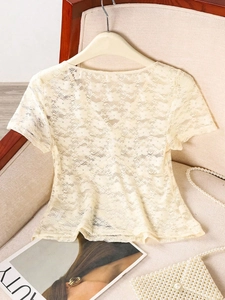 Close-up of beige floral lace short sleeve top with elegant pearl accessories