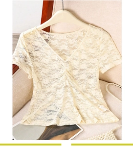 Detail of cream floral lace blouse featuring V-neckline and delicate ruffled chest accents