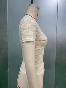 Detailed side view of a white lace short sleeve top featuring intricate floral patterns