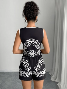 Detailed back view of a black sleeveless romper featuring a bold white floral pattern print