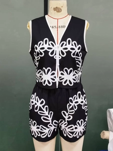 Detailed view of black V-neck vest and shorts set with white floral embroidery accents