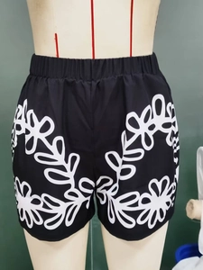 Detail of black summer shorts featuring white floral print and comfortable elastic waistband