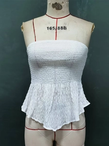 Detailed view of white smocked tube top with elastic texture and ruffle hem detail