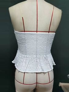 Detail of white smocked tube top showing elastic pleated texture and ruffled hemline