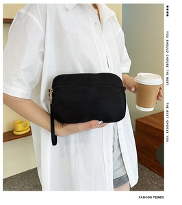 Close-up of minimalist black nylon wristlet bag featuring a premium gold metal zipper