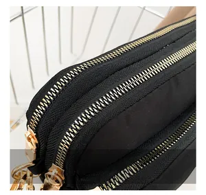 Close-up of smooth gold metal dual zippers on a black nylon crossbody bag