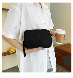 Detail of waterproof black nylon crossbody bag with dual zippers and portable wrist strap