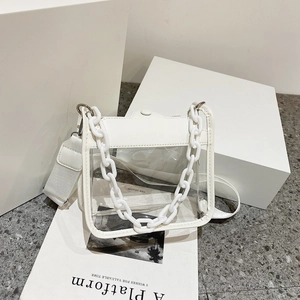 Détail du sac bandoulière en PVC transparent avec chaîne blanche et large sangle textile