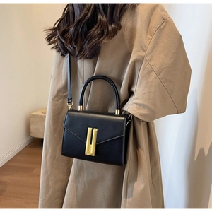 Detailansicht der schwarzen Quadratischen Tasche mit Ledertextur und goldener Metallschnalle