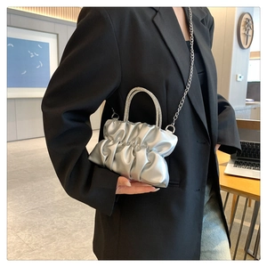 Detail of silver pleated cloud bag with sparkling rhinestone handles and chain strap