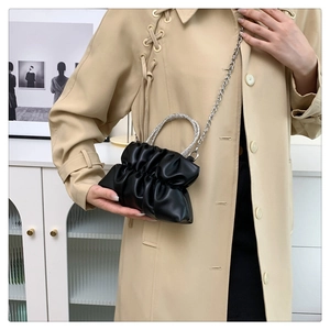 Detail of black pleated cloud bag with sparkling rhinestone handle and silver chain strap