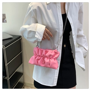 Detail of pink ruched handbag featuring rhinestone ring handle and silver chain strap