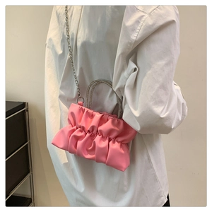 Close-up of pink pleated cloud bag with rhinestone handles and silver chain strap