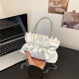 Detail of white pleated cloud bag featuring rhinestone handles and silver chain strap