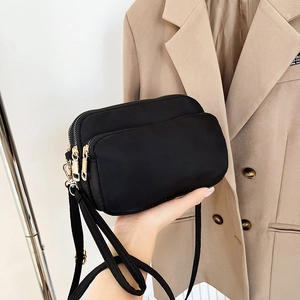 Black waterproof nylon crossbody bag with three zipper layers and gold hardware details