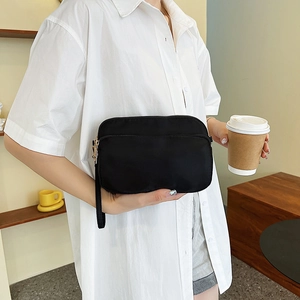 Minimalist black nylon crossbody square bag with multiple zipper layers and wrist strap