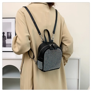 Close-up of a black rhinestone backpack worn with a beige trench coat for a chic look