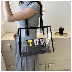 Detail of transparent PVC tote bag with STUFF towel embroidery and black faux leather trim